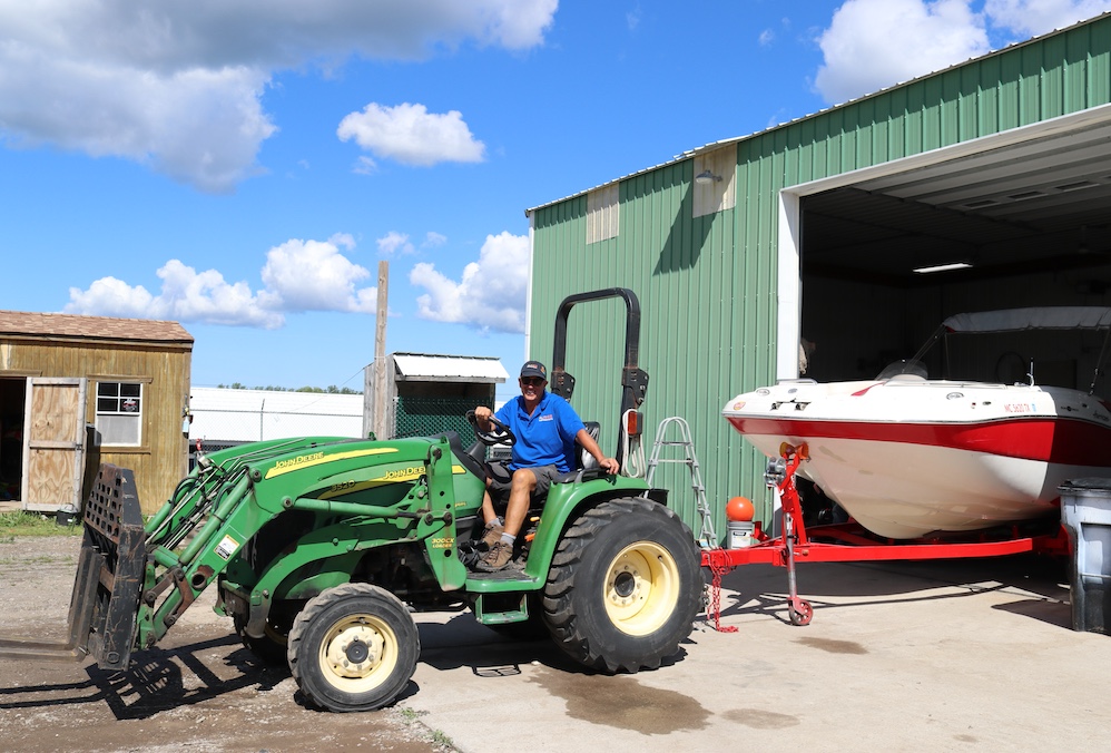 aussie crew member tow boat out of garage on a green tractor 